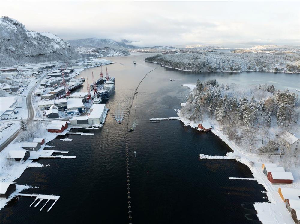 Slep av sjøleidning gjennom sund med småbåtar som hjelper til - Klikk for stort bilete