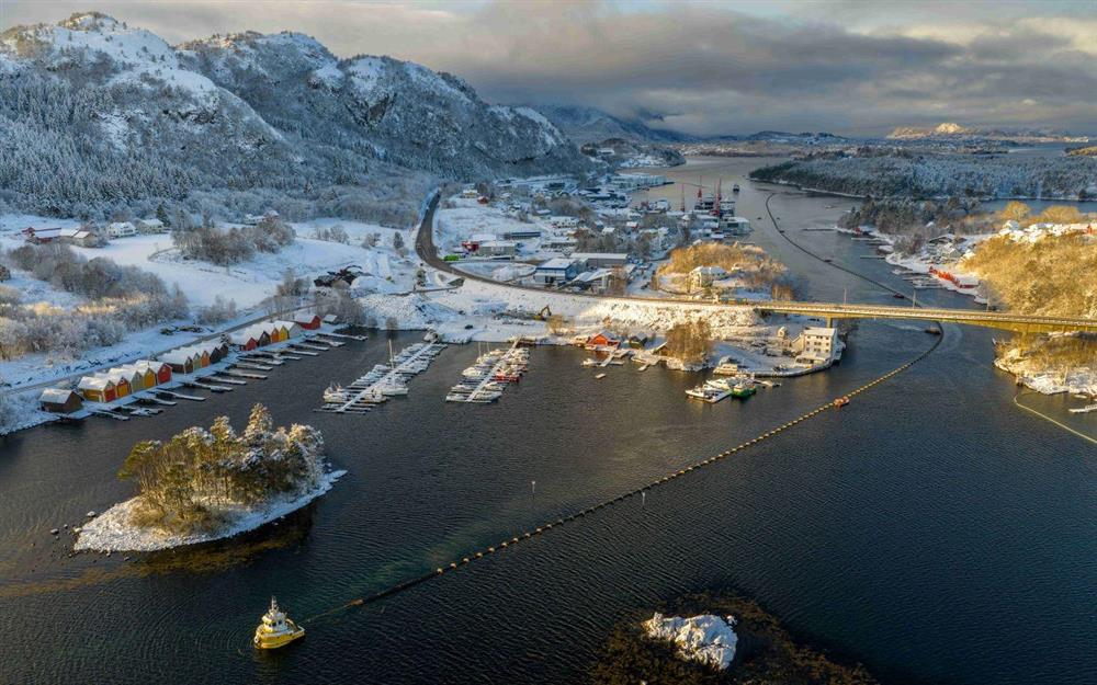 Slep av sjøleidning gjennom sund med småbåtar som hjelper til - Klikk for stort bilete