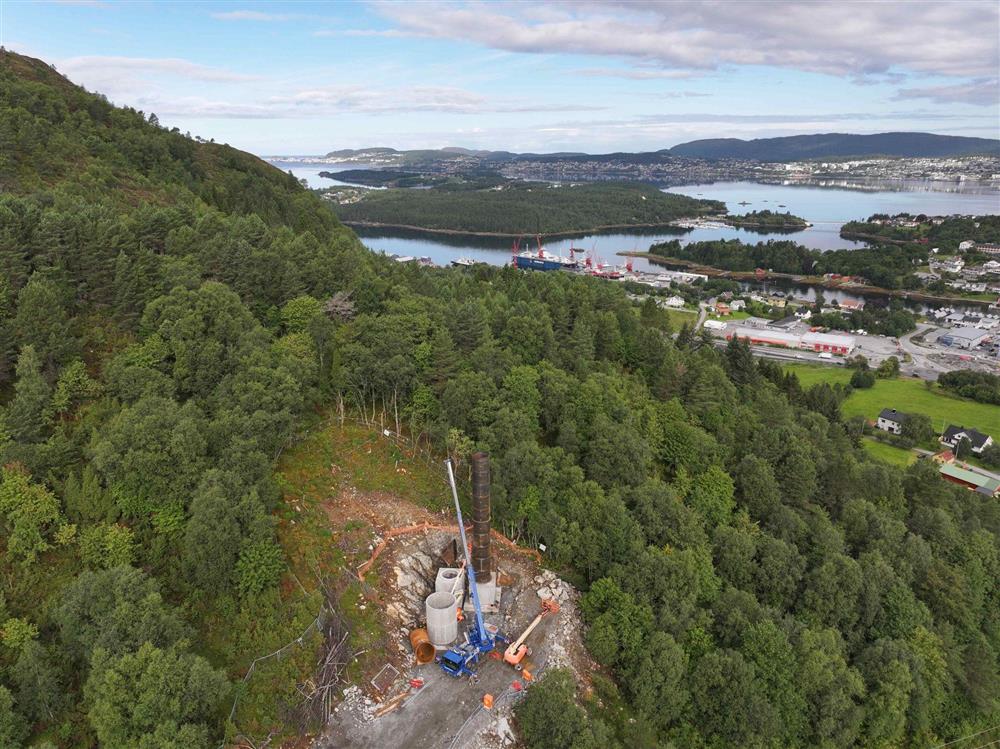 grøn natur med anleggsområde i front og busetnad i bakgrunnen - Klikk for stort bilete