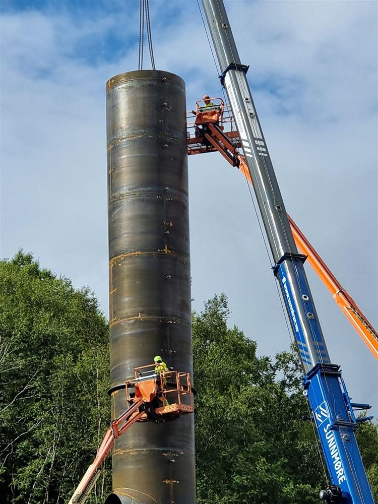 industripipe, heisekran og personar i lift - Klikk for stort bilete