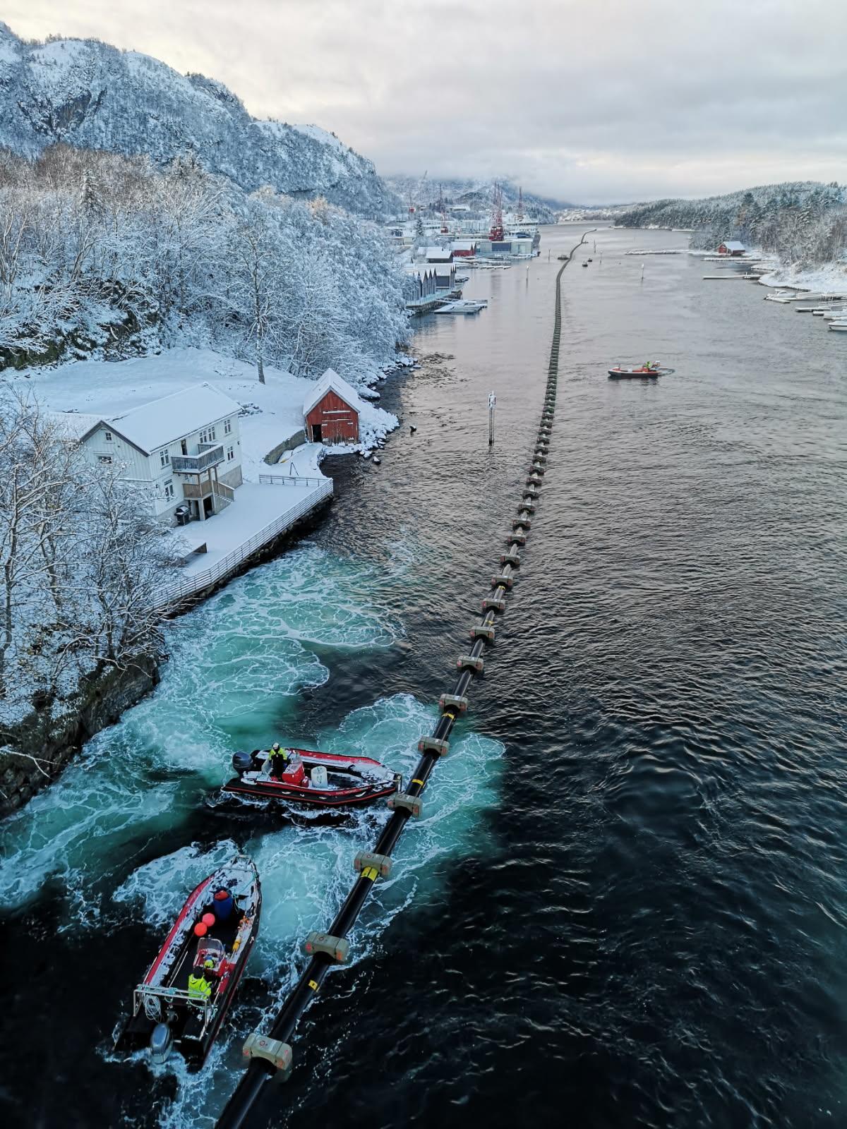 slep av sjøleidning gjennom sund med båtar som hjelper til - Klikk for stort bilete