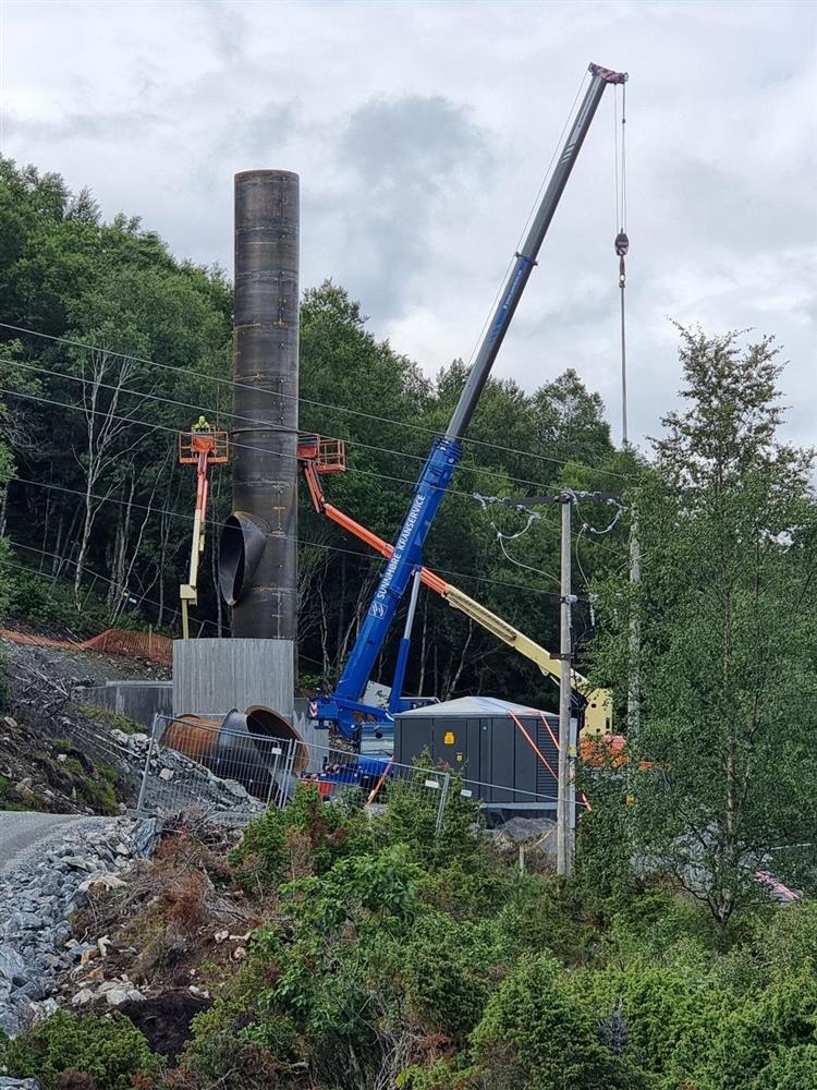 industripipe, heisekran og personar i lift - Klikk for stort bilete
